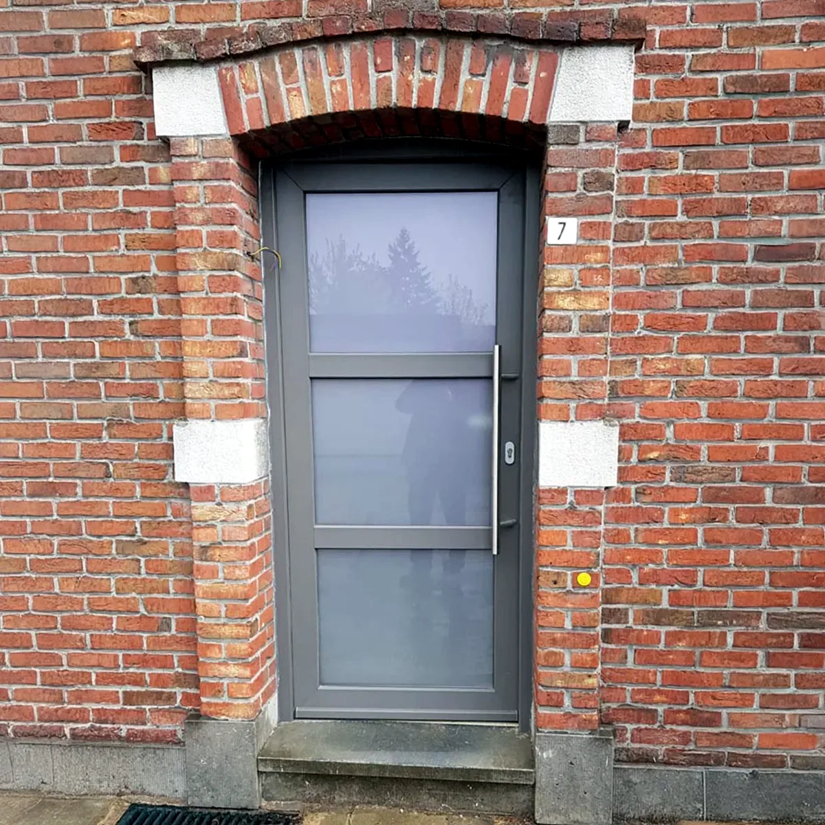 Antracietkleurige PVC voordeur in een bakstenen gevel