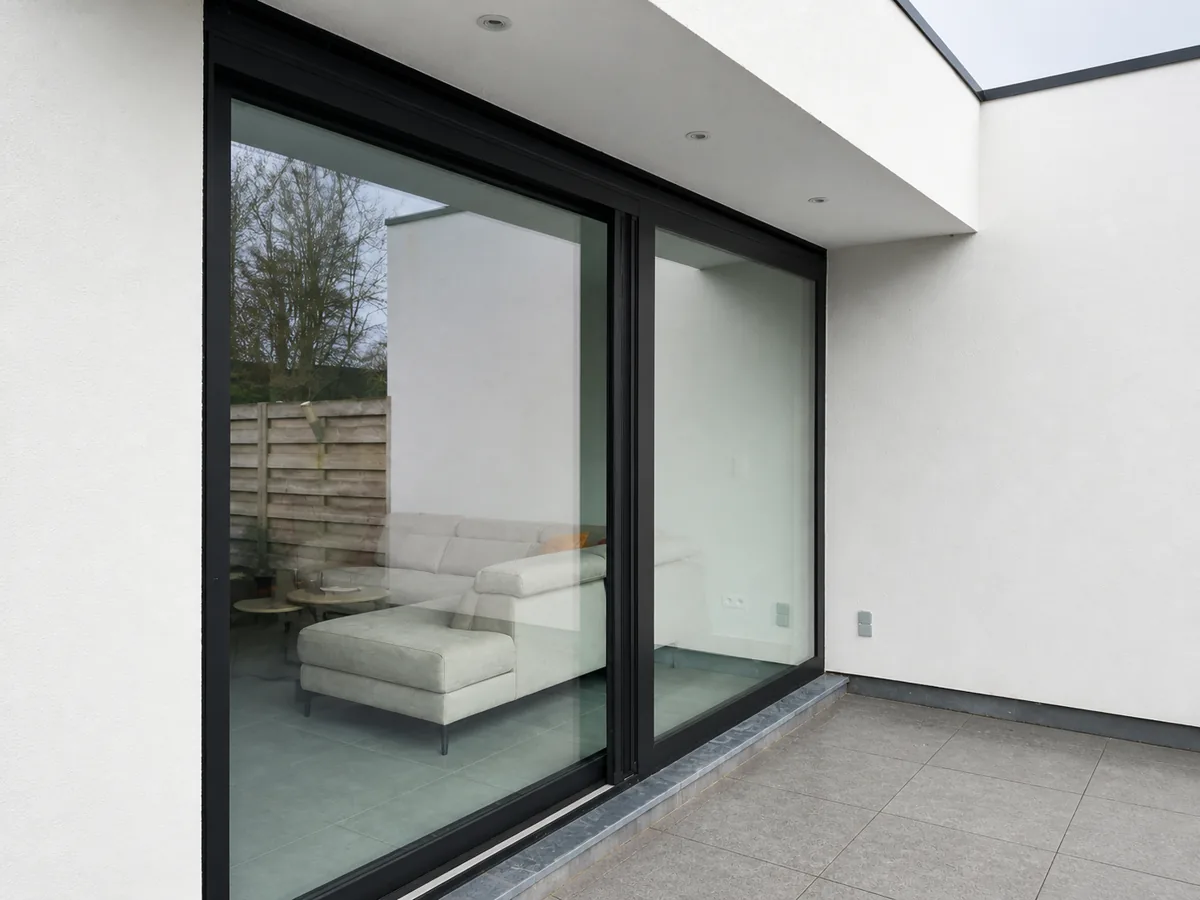 Fenêtre coulissante en aluminium noir avec de grandes surfaces vitrées dans une façade arrière blanche